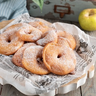 Frittelle di mele fritte e dorate, abbondantemente spolverizzate di zucchero a velo