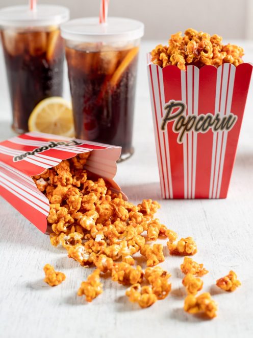 Popcorn al caramello salato che fuoriescono da un contenitore rovesciato