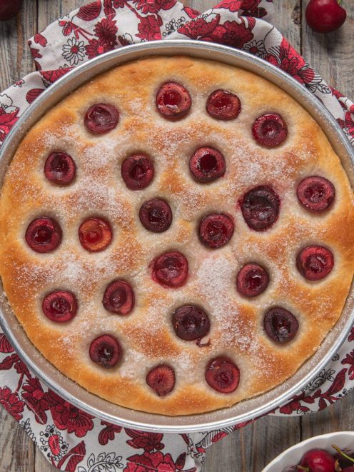 Focaccia alle ciliegie appena sfornata, con ciliegie intere affossate nell'impasto e zucchero in superficie