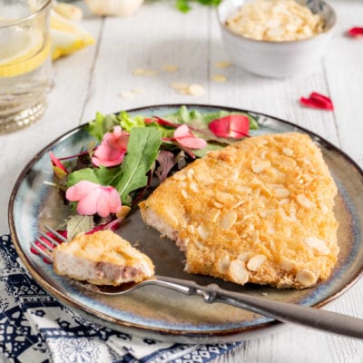 Cotoletta di pesce spada impanata con mandorle a lamelle, servita con insalatina e fiori eduli