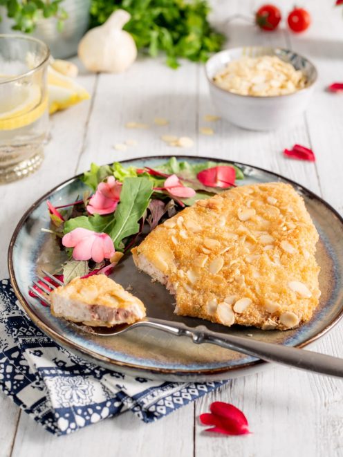 Cotoletta di pesce spada impanata con mandorle a lamelle, servita con insalatina e fiori eduli