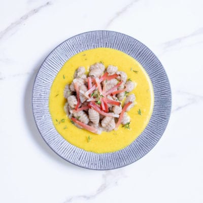 Gnocchetti di grano saraceno con speck su crema gialla, guarniti con striscioline rosse e timo fresco