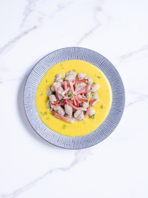 Gnocchetti di grano saraceno con speck su crema gialla, guarniti con striscioline rosse e timo fresco