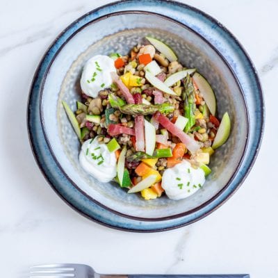 Insalata di verdure, cereali e speck con asparagi, zucchine, mela e quenelle di skyr