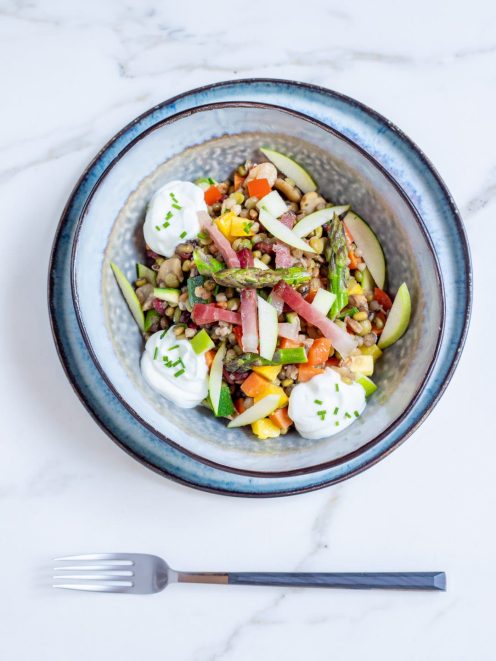 Insalata di verdure, cereali e speck con asparagi, zucchine, mela e quenelle di skyr