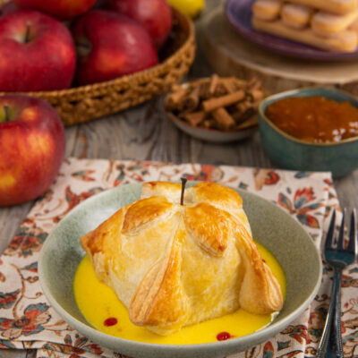 Mela in gabbia di pasta sfoglia dorata servita con crema inglese e gocce di coulis di lamponi
