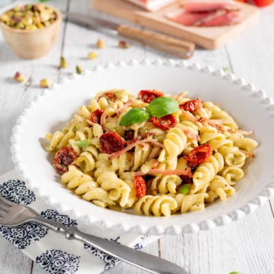Pasta con pesto di pistacchi, speck e pomodorini confit con foglie di basilico fresco