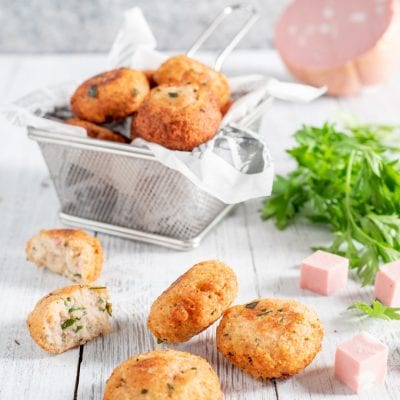 Polpettine di ricotta e mortadella fritte, una spezzata mostra il ripieno con prezzemolo