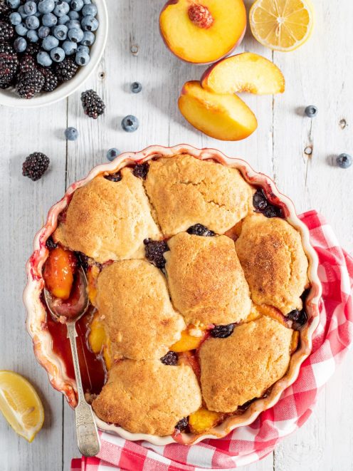 Cobbler con pesche e frutti di bosco, coperto da biscotti dorati e croccanti appena sfornati