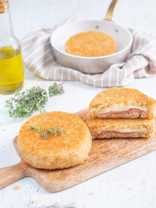 Supplì di riso dorati e panati, uno tagliato a metà con ripieno di mozzarella filante e salume