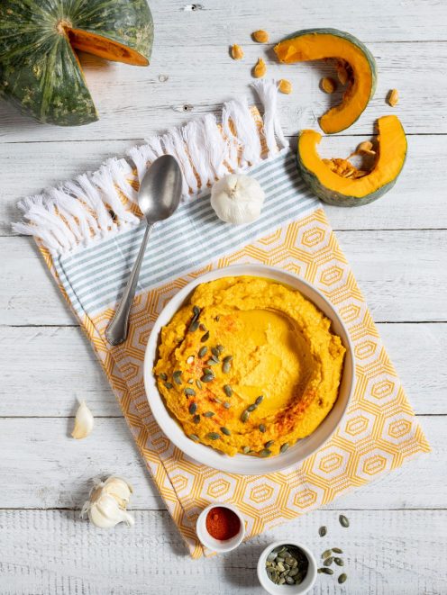 Hummus di zucca guarnito con semi di zucca e paprika, servito con zucca fresca e aglio