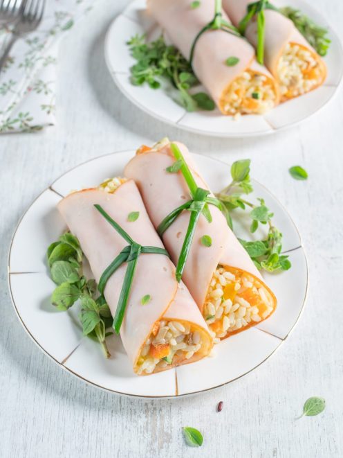 Involtini di tacchino ripieni di riso con verdure, legati con erba cipollina e guarniti con germogli freschi