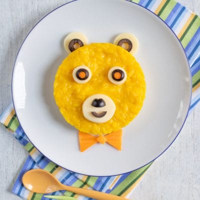 Orsetto riso allo zafferano decorato con olive, mozzarella e carota a forma di faccina sorridente