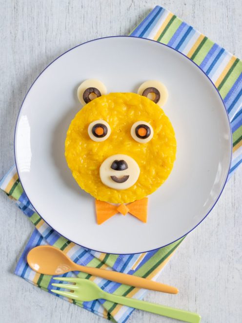 Orsetto riso allo zafferano decorato con olive, mozzarella e carota a forma di faccina sorridente
