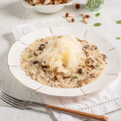 Risotto ai funghi con salsiccia, guarnito con scaglie di raspadura al centro