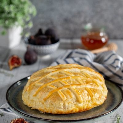 Scrigno di pasta sfoglia dorata con camembert e fichi freschi tagliati accanto