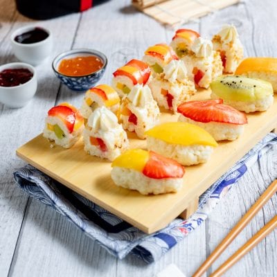 Sushi di frutta con fragole, mango, kiwi e ciuffi di panna su base di riso dolce
