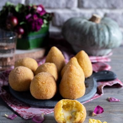 Arancini di zucca fritti con cuore di formaggio filante, uno spezzato in primo piano