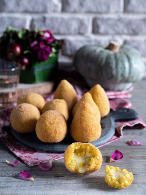 Arancini di zucca fritti con cuore di formaggio filante, uno spezzato in primo piano