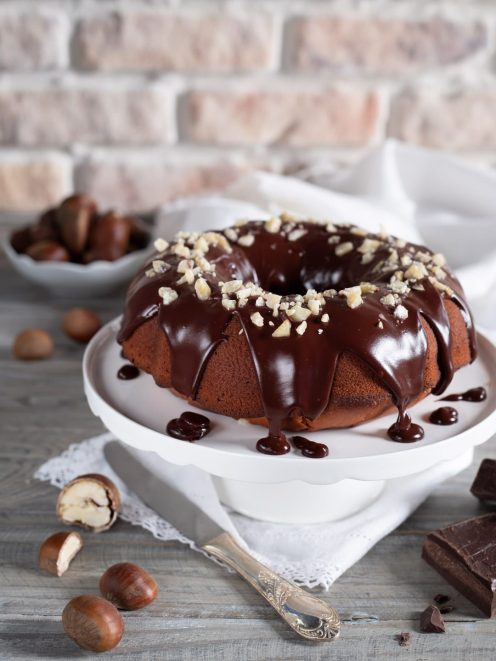 Ciambella di castagne con glassa al cioccolato colante e granella di nocciole in superficie