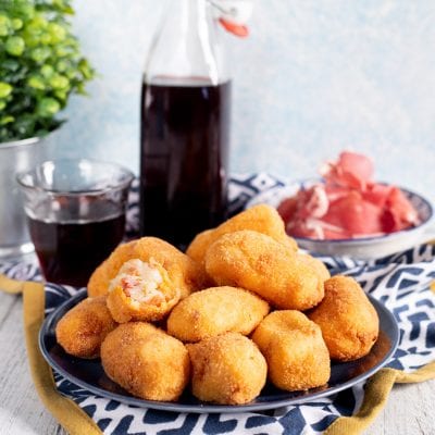 Crocchette di Jamon Serrano fritte e dorate, una aperta che rivela il ripieno filante