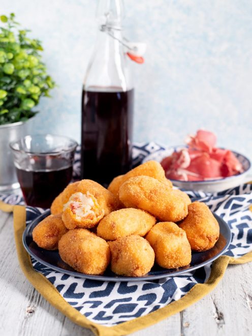 Crocchette di Jamon Serrano fritte e dorate, una aperta che rivela il ripieno filante