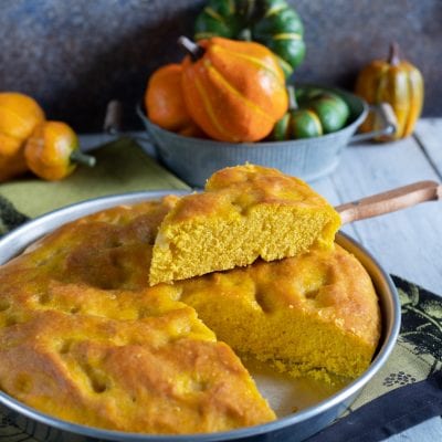 Focaccia alla zucca con una fetta sollevata che mostra la mollica soffice e dorata