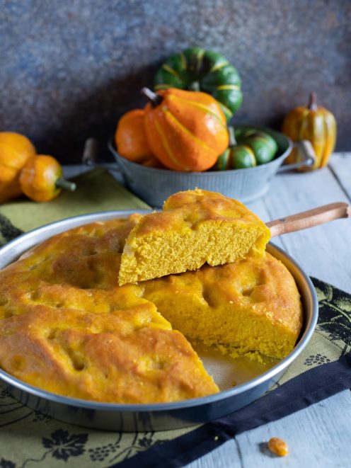Focaccia alla zucca con una fetta sollevata che mostra la mollica soffice e dorata