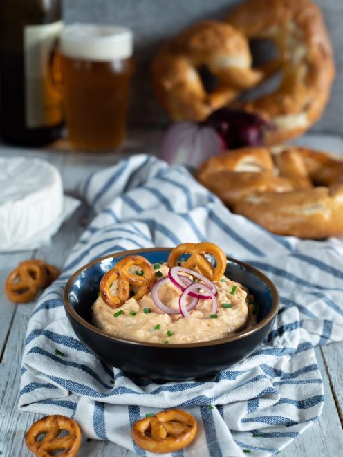 Obatzda cremoso guarnito con rondelle di cipolla rossa, erba cipollina e bretzel piccoli