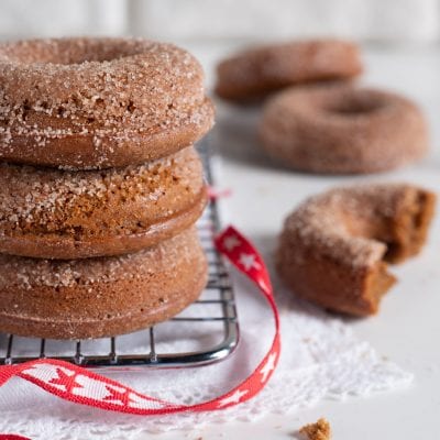Gingerbread donuts impilati su griglia, ricoperti di zucchero granulato, con uno spezzato accanto