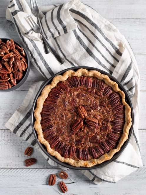 Pecan pie con ripieno caramellato e noci pecan disposte a cerchio sulla pasta frolla