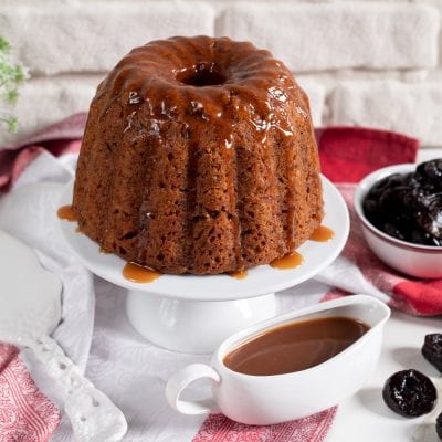 Pudding alle prugne e salsa mou glassato al caramello, servito intero con salsiera e prugne secche