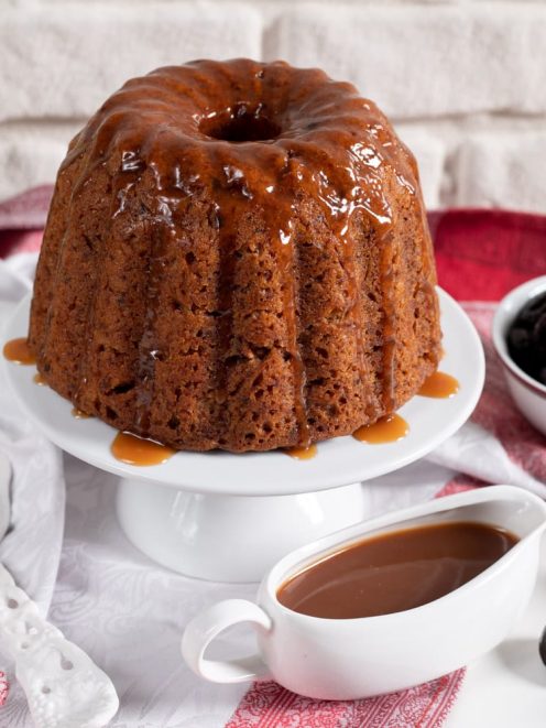 Pudding alle prugne e salsa mou glassato al caramello, servito intero con salsiera e prugne secche
