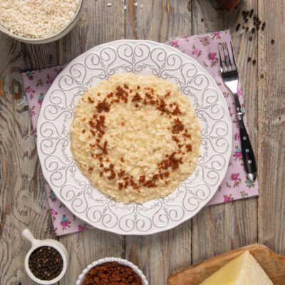 Risotto cacio e pepe mantecato, guarnito con briciole croccanti di pepe tostato