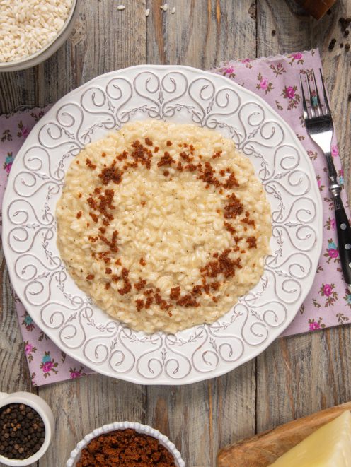 Risotto cacio e pepe mantecato, guarnito con briciole croccanti di pepe tostato
