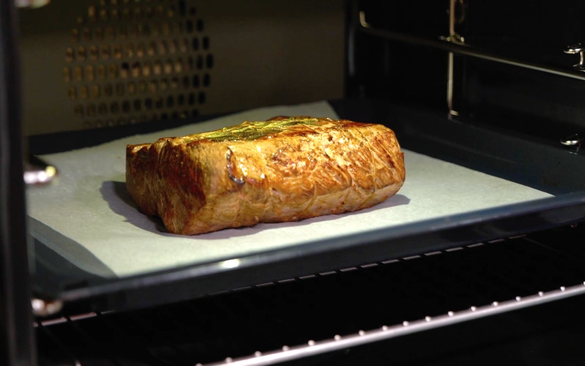 Roast beef in cottura nel forno, con la crosta ben dorata e le erbe aromatiche visibili sulla superficie