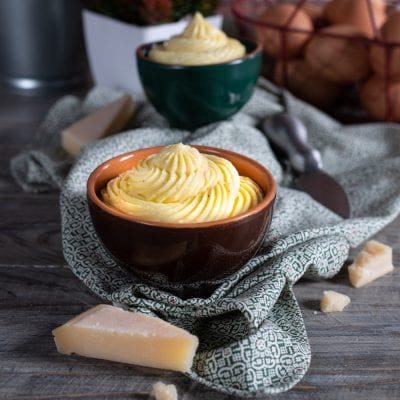 Crema pasticcera al Parmigiano servita a ciuffo con scaglie di formaggio accanto