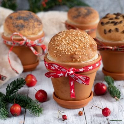 Panini di Natale cotti in vasi di terracotta, guarniti con semi di sesamo, papavero e pinoli