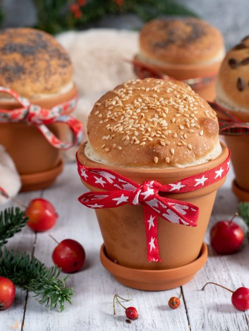 Panini di Natale cotti in vasi di terracotta, guarniti con semi di sesamo, papavero e pinoli