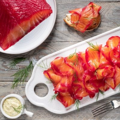 Salmone gravlax affettato sottile con bordi rossi di barbabietola, guarnito con aneto fresco e servito con salsa