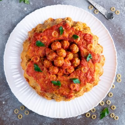 Sformato di anelletti a cupola con polpettine e sugo di pomodoro al centro, guarnito con prezzemolo