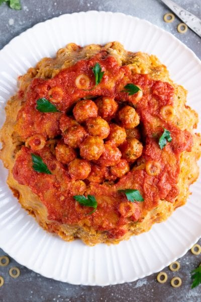 Sformato di anelletti a cupola con polpettine e sugo di pomodoro al centro, guarnito con prezzemolo