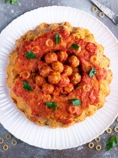 Sformato di anelletti a cupola con polpettine e sugo di pomodoro al centro, guarnito con prezzemolo