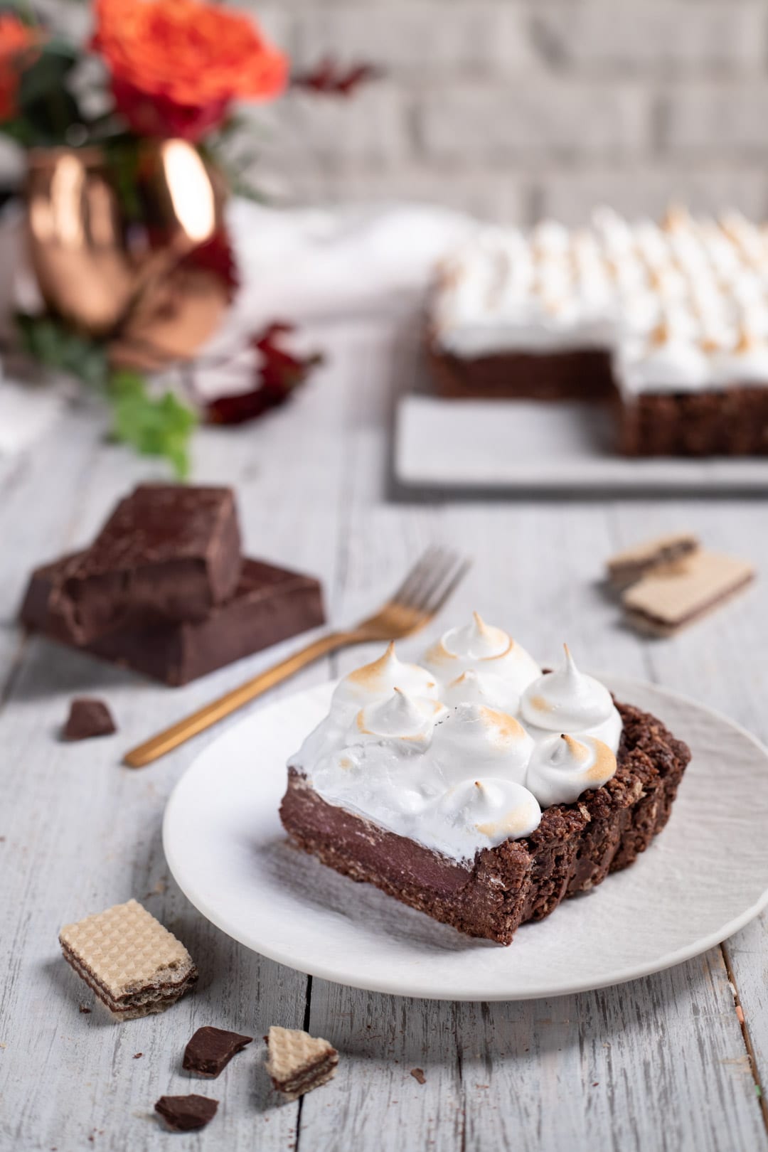 Fetta di torta meringata al cioccolato con ciuffi di meringa tostata su base di wafer e crema