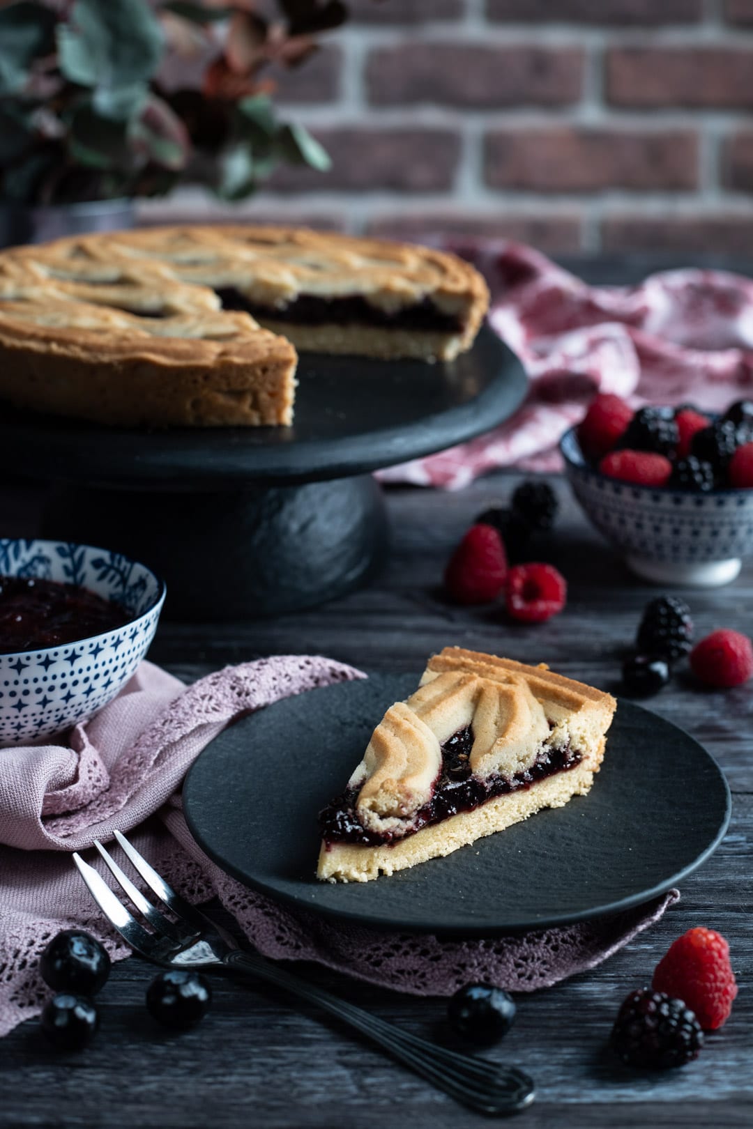 Fetta di crostata con frolla montata e ripieno di marmellata ai frutti di bosco