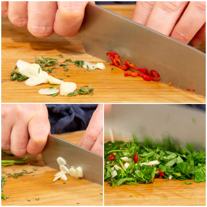 Aglio, peperoncino rosso ed erbe aromatiche tritati al coltello su tagliere di legno