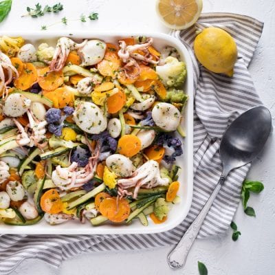 Moscardini con verdure al vapore: calamari, zucchine, carote, cavolfiore colorato e erbe aromatiche