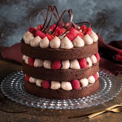 Naked cake al fondente a tre strati con crema al cioccolato, lamponi freschi e riccioli di cioccolato fondente