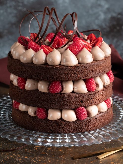 Naked cake al fondente a tre strati con crema al cioccolato, lamponi freschi e riccioli di cioccolato fondente