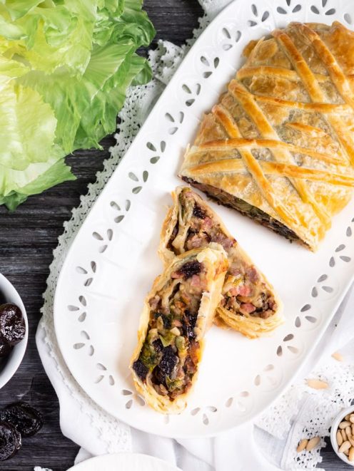 Strudel salato con scarola e prugne affettato, con il ripieno scuro e ricco ben visibile